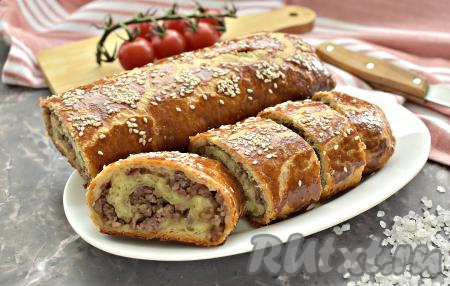 Рулет из слоёного теста получился румяным и очень вкусным, с сочной начинкой из фарша внутри. Слегка остужаем выпечку, нарезаем на кусочки и угощаемся.