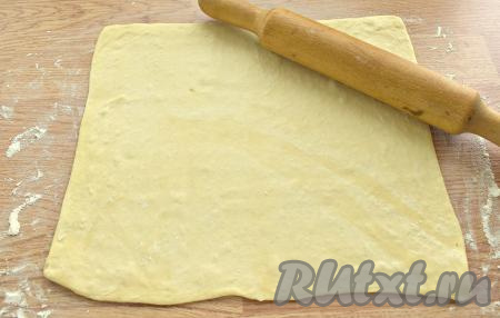 Стол посыпаем мукой, выкладываем размороженный пласт слоёного теста и раскатываем его в прямоугольник (примерный размер 31 сантиметр на 27 сантиметров).