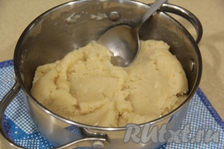 Снять кастрюлю с огня и хорошо перемешать тесто ложкой, тщательно вмешивая всю муку. Заварное тесто для профитролей получится очень пластичным и однородным.