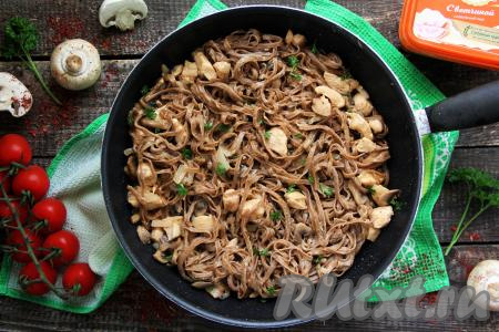 Добавить лапшу в сковороду с курицей и грибами, прогреть, перемешивая, в течение 3 минут, а затем вкусное, сытное блюдо можно раскладывать по тарелкам и подавать к столу.