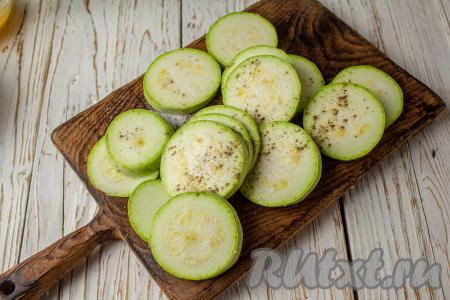 Кабачок промойте и обсушите (если у кабачка шкурка тонкая, её можно не срезать). Для этого блюда очень важно выбирать кабачки с мелкими семечками. Нарежьте подготовленный кабачок на кружочки толщиной примерно 1 сантиметр, посолите их и поперчите.