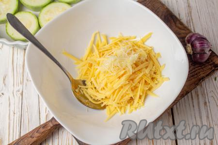 Подготовьте начинку для кабачков, для этого сыр, натёртый на средней тёрке, выложите в миску, добавьте натёртые на мелкой тёрке (или пропущенные через пресс) зубчики чеснока.&nbsp;