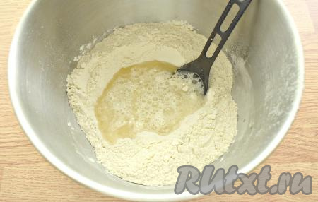 В мучную смесь вливаем растительное масло и тёплую воду (температура воды, примерно, 38 градусов), перемешиваем вначале ложкой.