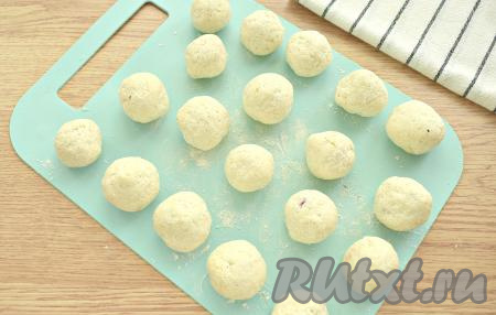 Края каждой лепёшки собираем над вишенкой, пряча начинку и формируя заготовку творожного пончика. Заготовки пончиков катаем в ладонях, придавая им форму шарика.