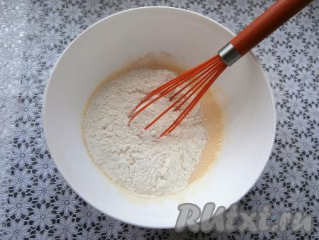 Затем частями начать всыпать муку, каждый раз хорошо перемешивая тесто для пончиков вначале венчиком, а затем переложить его на стол (или силиконовый коврик), присыпанный мукой, и хорошо вымесить.