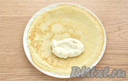 Перемешиваем блинное тесто перед выпечкой каждого блина, чтобы оно не застаивалось. Хорошо прогреваем смазанную маслом поверхность сковороды, огонь убавляем до среднего, вливаем половник теста, равномерно распределяем и жарим блинчик до подрумянивания с двух сторон (примерно по 1 минуте с каждой стороны), затем перекладываем его на тарелку. Когда готовый блинчик чуть-чуть остынет, выкладываем на него столовую ложку творожной начинки.