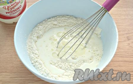 В мучную смесь вливаем тёплое молоко и добавляем 1 столовую ложку растительного масла, перемешиваем тесто венчиком.