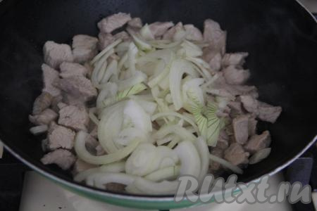 К обжаренной индейке выложить лук, нарезанный полукольцами, перемешать.