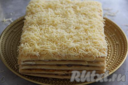 Затем положить следующий корж и слегка прижать. Смазать его майонезом и присыпать натёртым сыром. После формирования дать закусочному торту "Наполеон" пропитаться пару часов в холодильнике.