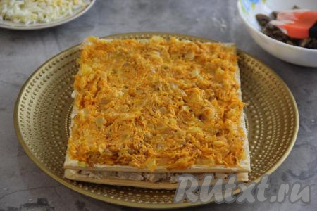 Накрыть начинку вторым коржом и прижать. Выложить начинку из моркови и равномерно распределить по коржу.