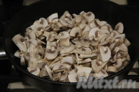 Когда жареные морковка с луком станут мягкими, их нужно переложить со сковороды на отдельную тарелку. Если готовите закусочный торт с шампиньонами, тогда промойте их и нарежьте на пластины. Шампиньоны (или предварительно отваренные лесные грибы) выложить в сковороду, уже прогретую с растительным маслом.