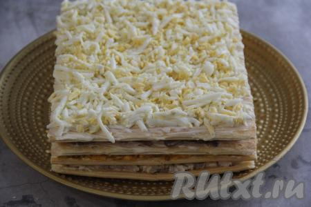 Накрыть ещё одним коржом и слегка прижать. Смазать корж майонезом и выложить начинку из яиц. Сделать сеточку из майонеза.