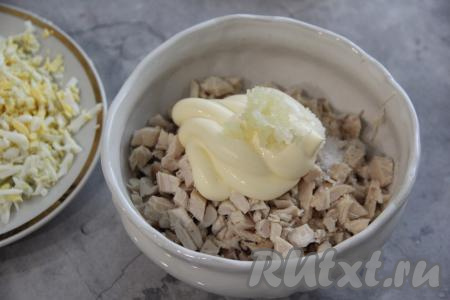 К нарезанному куриному мясу положить две столовые ложки майонеза и зубчик чеснока, пропущенный через пресс, присолить по вкусу и перемешать.