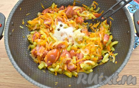 По истечении 5 минут к овощам всыпаем сахар, горошины перца и соль, добавляем натёртый на мелкой тёрке (или пропущенный через пресс) чеснок, перемешиваем и тушим 15 минут под крышкой, иногда помешивая, на минимальном огне.