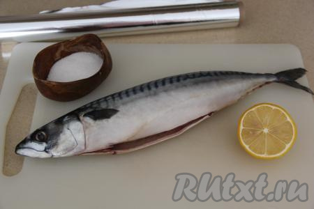Подготовить продукты для приготовления скумбрии, запечённой с лимоном в фольге в духовке. Рыбу полностью разморозить, удалить внутренности, не забывая вынуть из брюшка чёрную плёночку, промыть водой, затем обсушить. Взять половину вымытого лимона, отрезать 2-3 тонких кружочка, которые нужно разрезать пополам. Натереть скумбрию внутри и снаружи солью. Из оставшейся части лимона выдавить сок, поливая рыбку внутри и снаружи.
