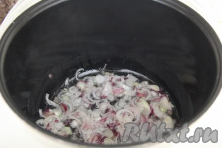 Влить растительное масло в чашу мультиварки, выставить режим "Жарка", выложить лук, нарезанный полукольцами, и обжарить его, минуты 2-3, помешивая.