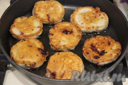 Жарить оладушки с ягодами на среднем огне до золотистости с двух сторон (примерно по 2 минуты с каждой стороны), затем переложить на тарелку. Аккуратно перемешать тесто, постепенно пожарить все оладушки.