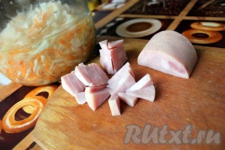 Ветчину нарезать кусочками. Когда маринованная капуста станет мягкой, добавить к ней ветчину,  обжаренные лук и перец, перемешать и потушить всё вместе минут 10. Затем добавить зелень, перемешать и оставить на 1-2 минуту на огне.
