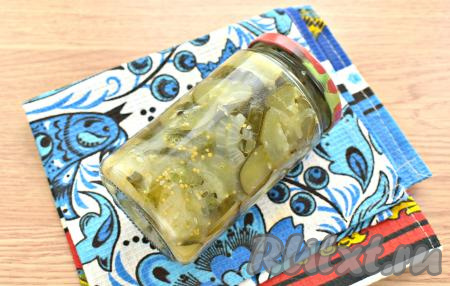 Горячий салат из огурцов перекладываем в сухие простерилизованные банки, закручиваем (или закатываем) их прокипячёнными крышками. Переворачиваем банки с салатом дном вверх, укутываем одеялом, оставляем полностью остывать. Хранить эту заготовку нужно в прохладном месте.