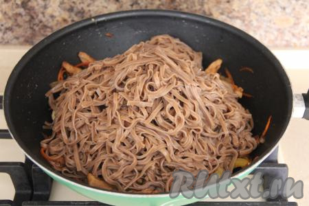 Затем в сковороду добавить гречневую лапшу, влить соевый соус, перемешать со свининой и овощами.