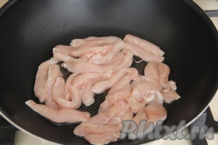 В сковороду с высокими бортиками (у меня - сковорода вок) влить масло и разогреть. Нарезать куриное филе на достаточно тонкие, длинные брусочки, выложить в сковороду с разогретым маслом. Параллельно на огонь поставить кастрюлю с водой, в которой будете варить удон.