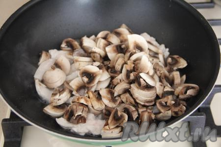 К обжаренной курице выложить шампиньоны, нарезанные на пластинки. Обжаривать мясо с грибами 10-15 минут (до готовности шампиньонов), иногда перемешивая.