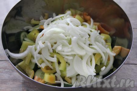 Лук нарезать полукольцами и выложить в миску с перцем и огурцами.