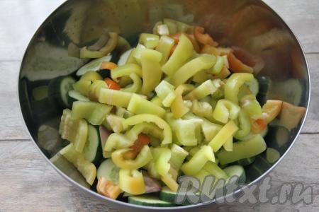 Перец очистить от семечек и плодоножек, нарезать на полоски и переложить к огурцам.