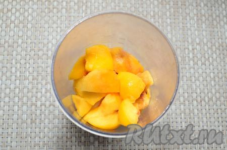 Персики очистить от кожуры, удалить косточку, нарезать на крупные дольки, выложить в чашу блендера поверх бананов.