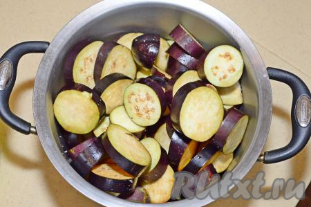 Баклажаны очистить от плодоножек, промыть, нарезать на кружочки толщиной 1,5-2 сантиметра (тонко нарезать не нужно, чтобы баклажаны не потеряли форму в процессе приготовления, но и толсто нарезать не нужно, чтобы овощи хорошо прожаривались, не впитывая при этом много масла). Присыпать баклажаны солью, перемешать, сложить в кастрюлю и оставить на 30-40 минут, чтобы ушла горечь. В это время нужно очистить морковку и лук, удалить семечки из болгарского перца. Напоминаю, что вес овощей в ингредиентах указан в очищенном виде.