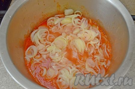 На дно большой кастрюли (у меня диаметром 28 см) влить немного томатного сока (я покрывая дно на высоту 1 сантиметр), выложить половину обжаренного лука.