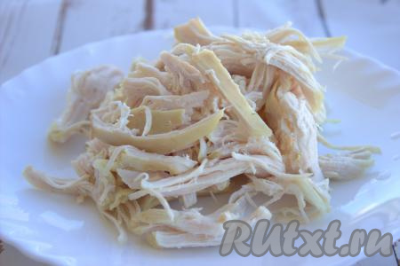 Из кастрюли вынуть курицу, дать немного остыть, затем отделить мясо от кости. Куриное мясо порвать на волокна.