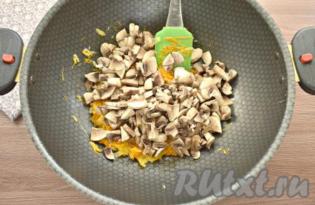 Шампиньоны хорошо промываем, нарезаем на небольшие кусочки и добавляем к обжаренным овощам, перемешиваем. Обжариваем грибы с луком и морковкой 5-6 минут, иногда перемешивая, затем снимаем с огня и даём немного остыть.