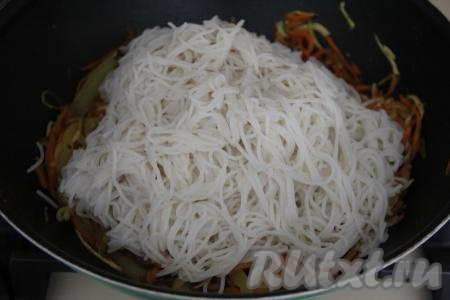 Добавить лапшу в сковороду с овощами.