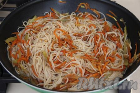 Перемешать рисовую лапшу с овощами, влить соевый соус, снова перемешать и прогреть на небольшом огне 5 минут, иногда помешивая.