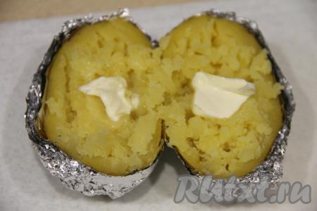 Готовую картошку разрезать на две части вместе с фольгой. С помощью вилки размять мякоть картошки. Добавить сливочное масло.