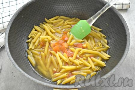 Макароны заливаем кипятком, перемешиваем. Доводим содержимое сковороды до кипения, накрываем крышкой и убавляем огонь до минимума. Тушим макароны с помидорами и луком около 10-12 минут.