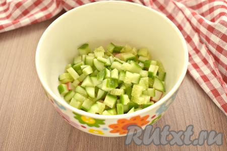 Моем свежий огурец, насухо его вытираем. Срезаем кончики и нарезаем огурчик на небольшие кубики, перекладываем в миску с крабовыми палочками.