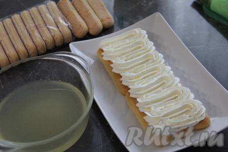 Крем из взбитых сливок и творожного сыра переложить в кулинарный мешок и отсадить поверх пропитанного печенья, выложенного на тарелку.