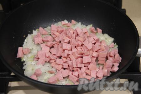 Сосиски очистить от слюды, мелко нарезать. Когда лук станет прозрачным, выложить к нему нарезанные сосиски, обжаривать минут 5, периодически помешивая, затем переложить на тарелку и дать немного остыть.