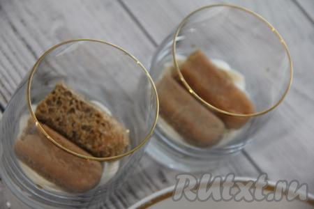 Переложить крем в кулинарный мешок. Печенье "Савоярди" разломать пополам. Обмакнуть каждую половинку печенья в кофе. На дно каждого стаканчика (я формировала трайфлы "Тирамису" в 3 стаканах) отсадить часть крема и выложить две половинки печенья.