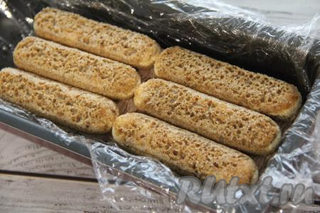 Выложить ещё слой печенья, смоченного в крепком кофе, покрыть его частью крема. Затем выложить третий слой печенья савоярди. Накрыть тирамису плёнкой и поставить в холодильник на ночь. Также на ночь убрать в холодильник остатки шоколадного крема.