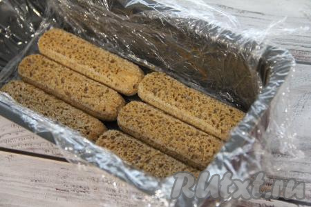 Выстелить форму пищевой плёнкой так, чтобы края плёнки свисали с боков формы (свисающими краями плёнки мы будем в дальнейшем накрывать сверху шоколадный тирамису). Окунать по одному печенью "Савоярди" в остывший кофе и выкладывать в форму в один слой. Я выложила 6 штук.