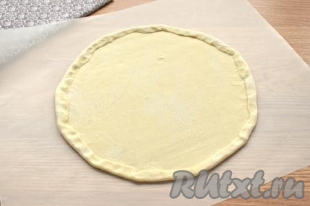 Размораживаем слоёное тесто при комнатной температуре. Отвариваем куриное филе в подсоленной воде до готовности (с момента закипания варим минут 20-25), затем достаём его из бульона и даём остыть. Размороженный пласт теста на присыпанной мукой поверхности раскатываем потоньше. Раскатанное тесто выкладываем на пергамент и, пользуясь крышкой (или тарелкой), вырезаем круг. Края круга (примерно, по 1,5 сантиметра) подгибаем к центру, формируя бортики. У меня получилась основа для пиццы диаметром 25 сантиметров. Остатки теста я просто запекаю, как печенье.