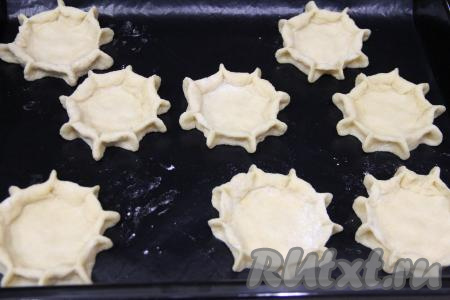 Защипать края каждой лепёшки, как на фото, и выложить песочную основу ватрушек на противень, застеленный ковриком для выпечки (или пергаментом). У нас получатся 8 заготовок песочных ватрушек.