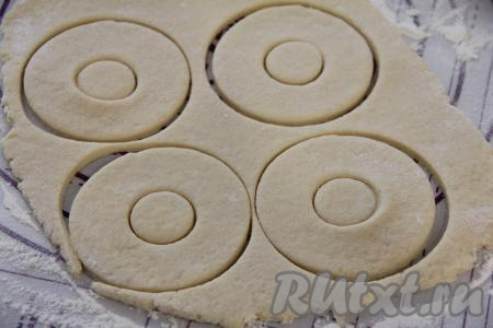 Отдохнувшее тесто на присыпанной мукой поверхности раскатать в пласт толщиной примерно 1 сантиметр. Вырезать колечки любого диаметра (у меня колечки диаметром 10 сантиметров). Большие колечки удобно вырезать кружкой, а маленькие колечки - пробкой от пластиковой бутылки.