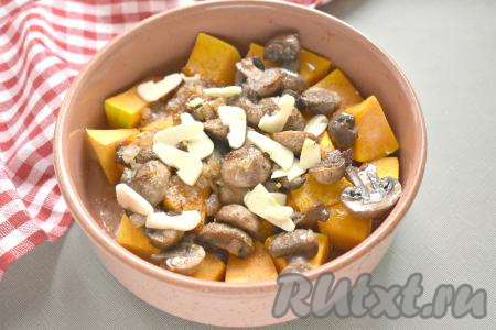 Солим тыкву с шампиньонами и луком, перчим по вкусу. Добавляем очищенные и нарезанные на пластинки зубчики чеснока.