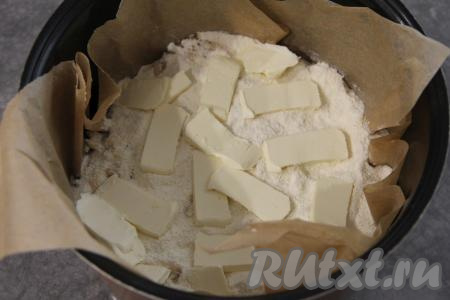 Выложить ещё одну часть смеси сухих ингредиентов, сверху равномерно разложить оставшиеся натёртые яблоки. Выложить третий слой сухих ингредиентов, сверху разложить тонкие кусочки сливочного масла.