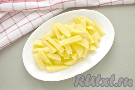 В кастрюлю вливаем 2 литра воды и доводим её на сильном огне до кипения, солим (добавляя соль, учитывайте, что в дальнейшем будет добавляться солёный огурчик). Очищаем картофель, нарезаем брусочками и отправляем в кастрюлю с кипящей водой. Даём воде с картошкой закипеть, уменьшаем огонь и варим 5 минут.