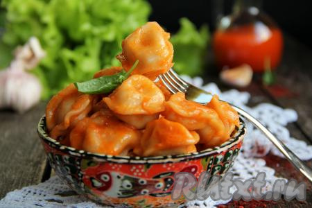 Переложить тушёные пельмени со сковороды на тарелку и подать к столу в горячем виде. По желанию, можно посыпать пельмени зеленью, а отдельно предложить соус, в котором они тушились.